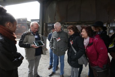 Gruppe aus Teilnehmern schauen auf Tablet des Gästeführers