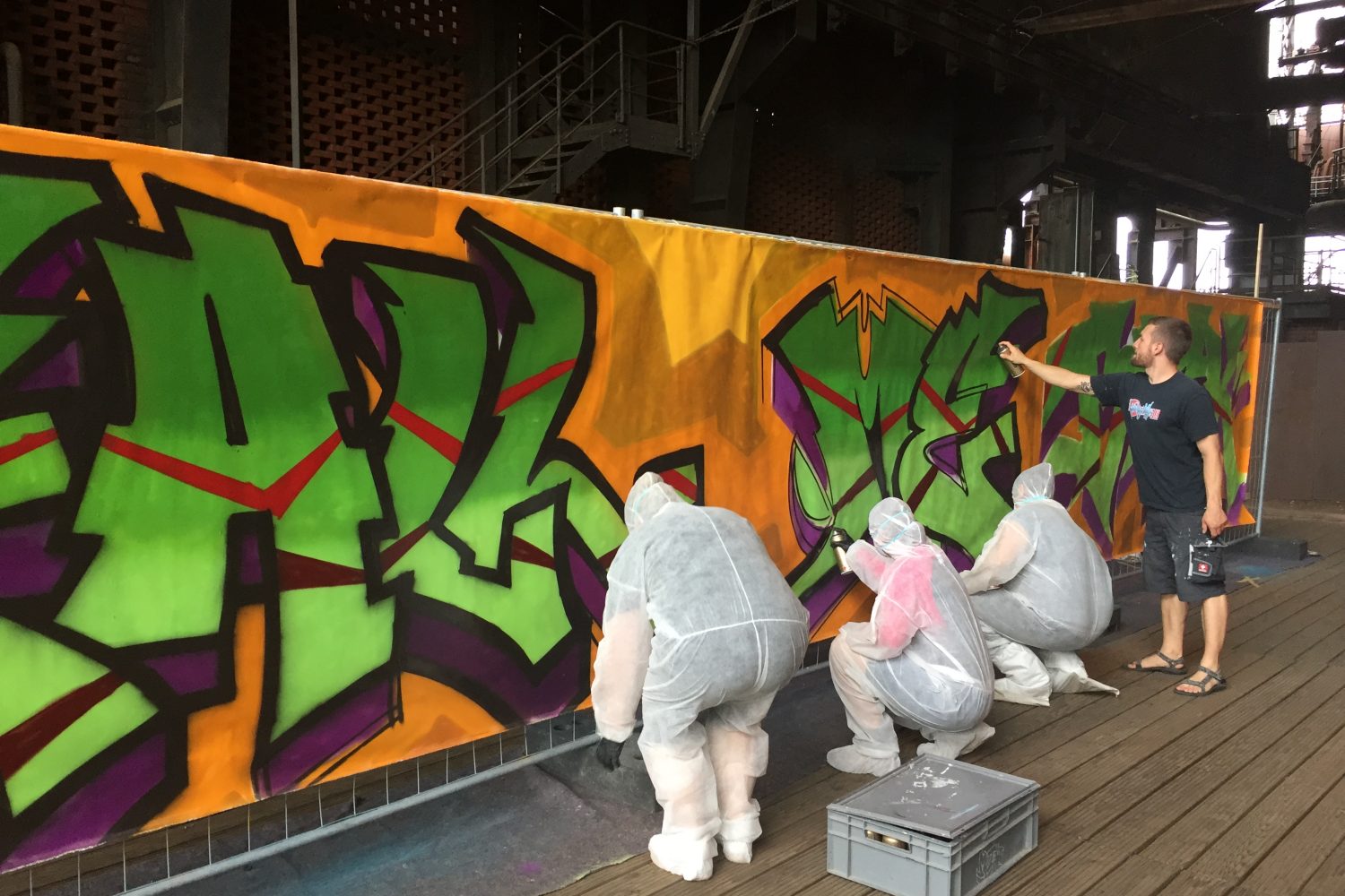 Personen bemalen Graffiti Wand in Schutzanzügen